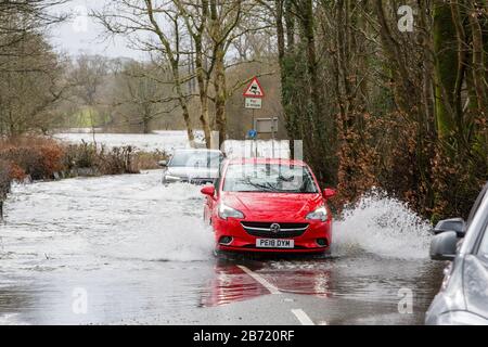 Überschwemmungen durch Storm Ciara an der Rothay Bridge in Ambleside, Lake District, Großbritannien, mit Autos durch die Überschwemmungen. Stockfoto