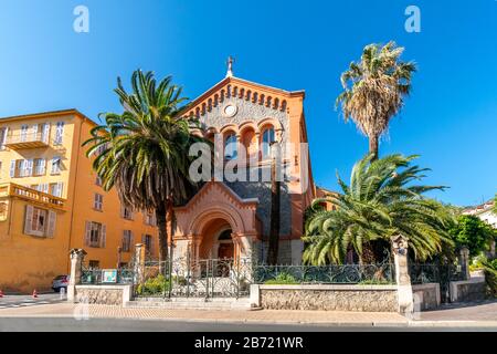 Die malerische Reformierte Protestantische Kirche von Frankreich, umgeben von Palmen in der mediterranen Stadt Menton, Frankreich. Stockfoto