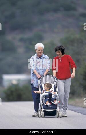 Mutter und Schwiegermutter schieben den zehn Monate alten Jungen in den Kinderwagen. HERR ©Bob Daemmrich / Stockfoto