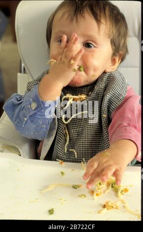 Austin Texas USA, 1995: 10 Monate alter Junge, der Spaghetti mit den Händen isst und unordentlich ist. HERR * Bob Daemmrich Stockfoto