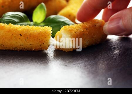 Panierte Mozzarella-Käsestäbchen mit Basilikum auf dem Tisch Stockfoto