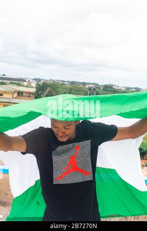 Stolz Nigeria. Foto eines jungen Afrika-Mannes, der seine Flagge hält und sagt, ich bin stolz darauf, ein Nigerianer, die Bundesrepublik Nigeria zu sein Stockfoto