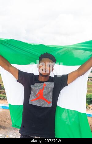 Stolz Nigeria. Foto eines jungen Afrika-Mannes, der seine Flagge hält und sagt, ich bin stolz darauf, ein Nigerianer, die Bundesrepublik Nigeria zu sein Stockfoto