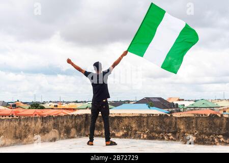 Stolz Nigeria. Foto eines jungen Afrika-Mannes, der seine Flagge hält und sagt, ich bin stolz darauf, ein Nigerianer, die Bundesrepublik Nigeria zu sein Stockfoto