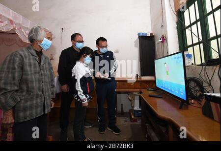 (200313) - Peking, 13. März 2020 (Xinhua) - Lehrer weisen Schüler Huang Yujuan (2. R) an, das Online-Klassensystem im Fernsehen in Taiping Town, Wuming District in Nanning City, Südchina Guangxi Zhuang Autonome Region, 12. März 2020 zu verwenden. Aufgrund des neuartigen Coronavirus-Ausbruchs wurde das neue Semester suspendiert und Studenten haben zu Hause Online-Kurse. Angesichts der Tatsache, dass sich einige armutsgeplagte Haushalte die Einrichtungen für Online-Kurse nicht leisten können, haben die Behörden Einrichtungen installiert, um den verarmten Schülern zu helfen, über Online-Kurse zu lernen. (Xinhua/Lu Boan) Stockfoto