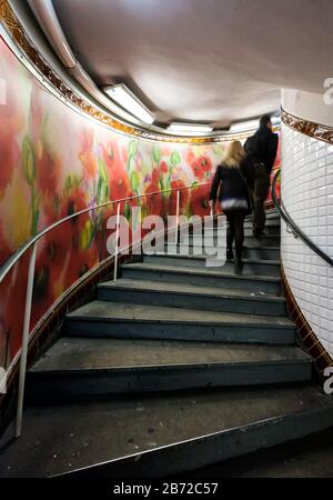 Menschen, die auf einer Seite Treppen mit einem farbenfrohen Blumenkraut in der U-Bahnstation Abbesses, Montmartre, Right Bank, Paris, Frankreich, Europa, Farbe klettern Stockfoto