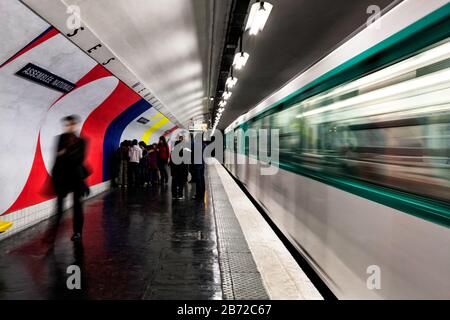 Ein abfahrender Zug in Bewegung, während die Passagiere zur Bahnsteigausfahrt an der U-Bahn-Station Assemblee-Nationale, Paris, Frankreich, Europa, Farbe laufen Stockfoto