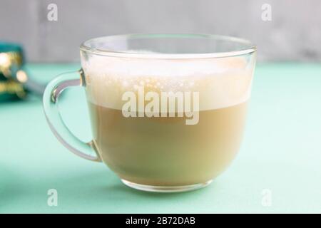 Latte Kaffee in elegantem, transparentem Glas mit Schlagsahne auf dem Minzgrund Stockfoto