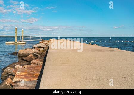 Leerer Pier am Strand, wunderschönes Meer, blauer Himmel. Betondock mit starkem Grafikhintergrund, Zementstruktur für den Kopierraum, Niantic, Coastal Connecticut USA Stockfoto