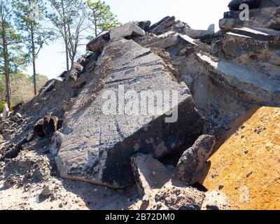 Berg aus Asphalt, Betonpflaster, Straßenbett und Parkplatz Trümmer am Road Demolition Site, Kiefern im Hintergrund, mittlere Sicht Stockfoto