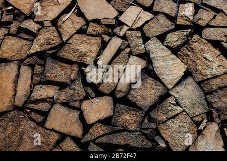 Natürlicher, brauner Stein unterschiedlicher Größe, zufällig platziert. Die Struktur der Steinwand. Steinwand von beliebiger Größe. Hintergrund der Steinmauer. Natur Stockfoto