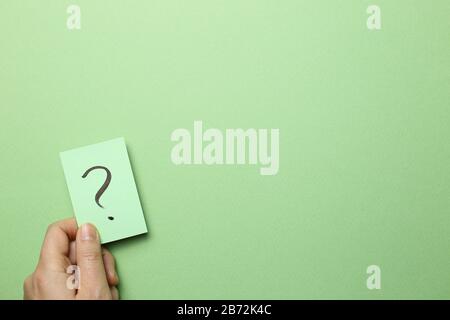 Halten Sie das Notizpapier mit Fragezeichen auf grünem Hintergrund. Lösungskonzept Stockfoto