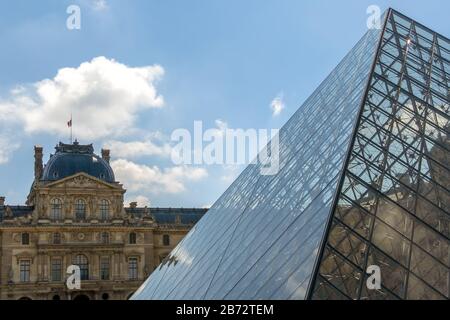 Frankreich. Sonniger Tag im Pariser Innenhof des Louvre Museums. Alte Fassade und moderne Glaspyramide Stockfoto