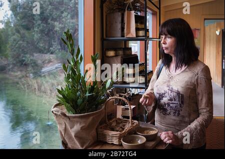 Weibliche Touristin schmeckt die aromatischen Einbrüche mit den organischen Brotstücken, während sie auf den Teich im Garten auf der Pheasant Farm im Barossa-Tal blickt. Stockfoto