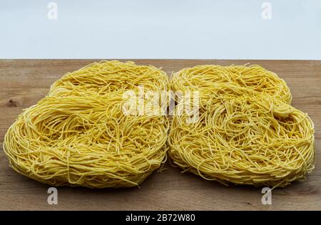 Raw Tagliolini auf Holztisch. Pasta Bio Eier und Mehl frisch, Nudeln all'uovo. Stockfoto