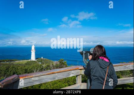 Blick auf den Cape Otway Lighthouse in Victoria, Australien als weibliche Touristin genießt die spektakuläre Szene des südlichen Ozeans hinter den Leitplanken Stockfoto