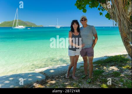 Ein Paar mit Blick auf die Kamera am Strand unter dem Baum im Fitzroy Island Resort in Queensland, Australien. Stockfoto