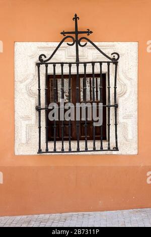 Antike Holz-Fenster mit schmiedeeisernen Gitter und geschnitzten Stein Rahmen an orange Wand. Stockfoto