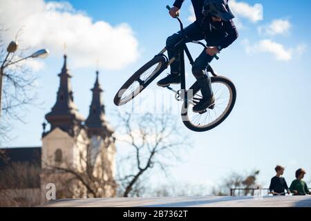 Junger Mann, der auf einem BMX-Fahrrad Tricks macht. BMX-Freistil vor dem Hintergrund der urbanen Landschaft. Extremsportarten sind in der Jugend sehr beliebt. Konzept des sp Stockfoto