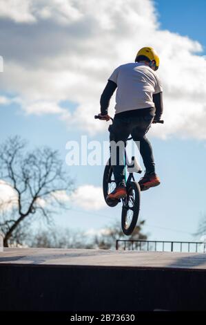 Junger Mann, der auf einem BMX-Fahrrad Tricks macht. BMX-Freistil vor dem Hintergrund der urbanen Landschaft. Extremsportarten sind in der Jugend sehr beliebt. Konzept des sp Stockfoto