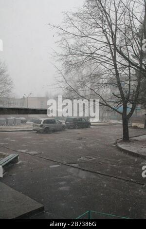 Plötzlich Schneesturm auf leerer Straße in der Stadt am Frühlingstag Stockfoto