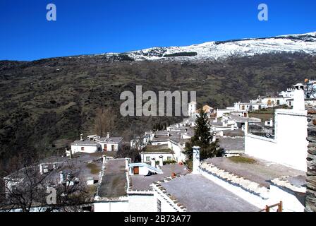 Gesamtansicht über die Dächer der Stadt in Richtung der Schnee begrenzt Berge, Bubion, Las Alpujarras, Provinz Granada, Andalusien, Spanien, Westeuropa. Stockfoto