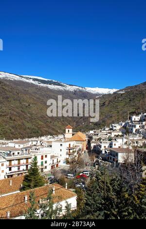 Blick über das weiße Dorf in Richtung der schneebedeckten Berge der Sierra Nevada, Pampaneira, Spanien. Stockfoto