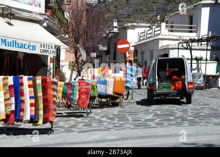 Vor Ort hergestellte Teppiche, die entlang der Haupteinkaufsstraße, Pampaneira, Spanien, Europa, verkauft werden. Stockfoto