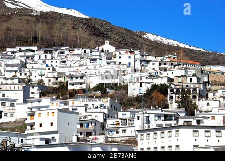 Dicht gepackte weiß getünchte Häuser des Dorfkerns (Pueblo blanco) mit schneebedeckten Bergen nach hinten, Trevelez, Spanien. Stockfoto