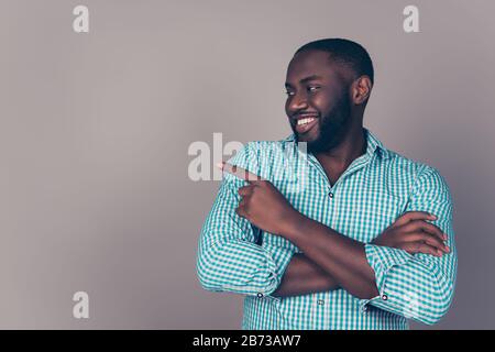 Porträt eines glücklichen afroamerikanischen bärtigen Mannes, der etwas auf den Kopierraum zeigt. Stockfoto