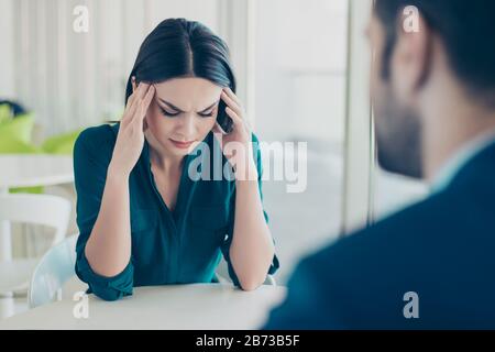 Bild zweier Arbeiter bei einem Treffen in einem Restaurant. Junge, ziemlich erschöpfte Geschäftsfrau, die wegen ihrer Probleme bei der Arbeit Kopfschmerzen hat. Stockfoto