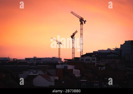 Silhouette von drei Kranen von einer Baustelle in Brüssel Belgien bei Sonnenuntergang in der Dämmerung Stockfoto