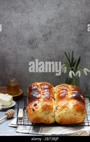 Traditionelle heiße Kreuzbrötchen mit Honig und Butter auf Betongrund. Stockfoto