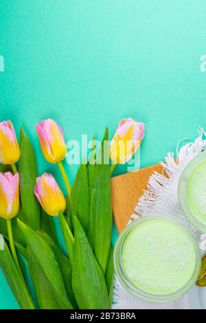 Minze Zitronenjoghurt mit Kiwi in Salatschüsseln auf einem Holzbrett sowie Tulpen auf pinkfarbenem Hintergrund Stockfoto
