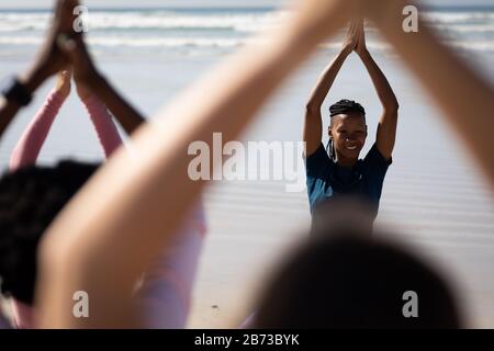 Rückansicht der Frauen, die am Strand Yoga machen Stockfoto
