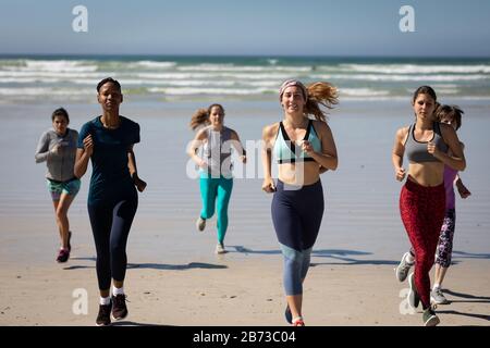Vorderansicht der Frauen, die am Strand laufen Stockfoto