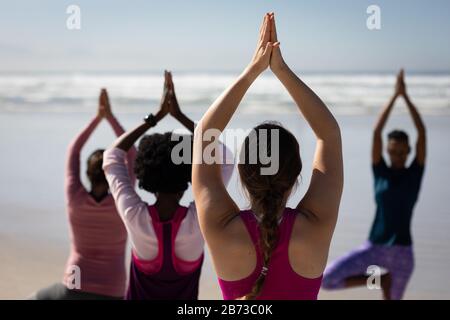 Rückansicht der Frauen, die Yoga-Positionen am Strand einnehmen Stockfoto