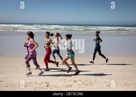 Seitenansicht der Frauen, die am Strand laufen Stockfoto