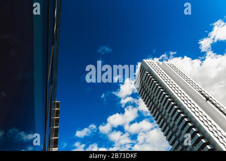 Ein tiefblauer Himmel spiegelt sich in den sauberen Glaswänden eines Gebäudes in einer Großstadt wider. Stockfoto