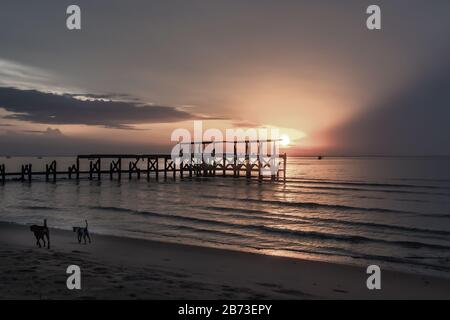 Blick auf zerbrochene alte Struktur Überreste von Pier im Meer. Kleine Welle krachend in die texturierten rostigen Pier Pfosten in der während der schönen Twiligh Stockfoto