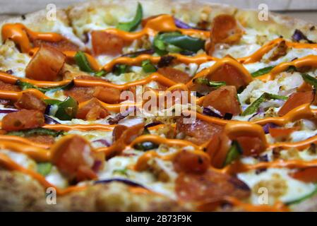 Pizza mit Pfefferoni- und Pfefferscheiben, mit Käse und heißer Orangensauce auf einem kunsthandwerklichen Papphintergrund, Seitenansicht. Stock-Foto für Web und Print. Stockfoto