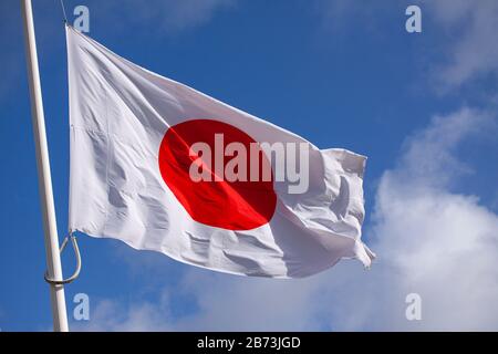 Japanische Flagge schwenkt im Wind gegen blauen Himmel. Nahaufnahme. Stockfoto
