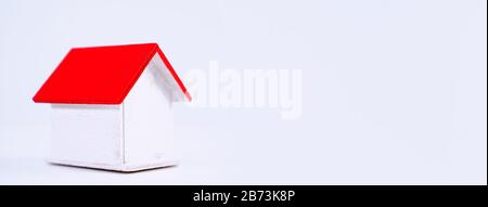 Finanzklage - Piggy Bank, wunderschönes rot-weißes Holzhausmodell auf weißem Hintergrund, spart Geld beim Kauf von Versicherungen, Nahaufnahme, Kopierplatz. Stockfoto