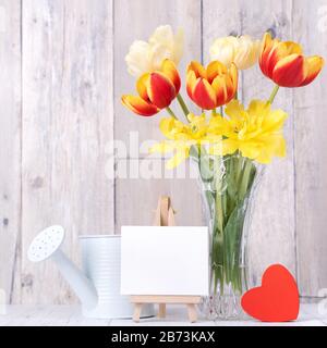 Tulpenblume in Glasvase mit Bilderrahmendekor auf Holztischhintergrundwand zu Hause, in der Nähe, Mother's Day Designkonzept. Stockfoto