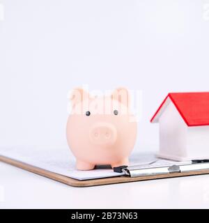 Finanzklage - Piggy Bank, wunderschönes rot-weißes Holzhausmodell auf weißem Hintergrund, spart Geld beim Kauf von Versicherungen, Nahaufnahme, Kopierplatz. Stockfoto