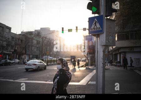 Teheran, Iran. März 2020. Eine Frau, die Maske trägt, überquert eine Straße in der Innenstadt von Teheran, Iran, am 12. März 2020. Im Iran beliefen sich die bestätigten Fälle einer COVID-19-Infektion am Donnerstag auf 10.075, ungefähr drei Wochen nach der ersten Meldung am 19. Februar. Die Zahl der Todesopfer aus dem Roman Coronavirus im Iran lag bisher bei 429. Kredit: Ahmad Halabisaz/Xinhua/Alamy Live News Stockfoto