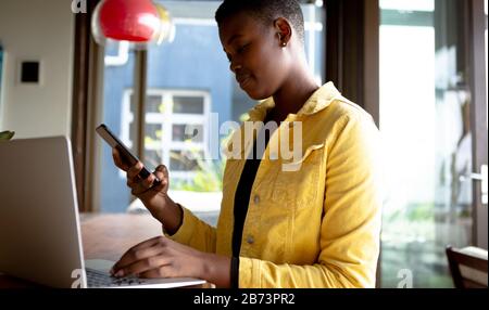 Frau, die am Laptop arbeitet, während sie am Tisch sitzt Stockfoto