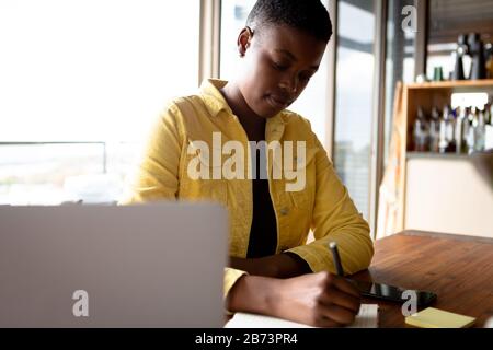 Frau, die am Laptop arbeitet, während sie am Tisch sitzt Stockfoto