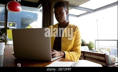 Frau, die am Laptop arbeitet, während sie am Tisch sitzt Stockfoto