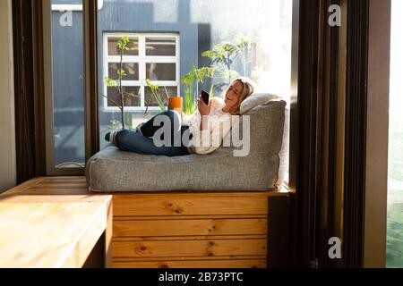 Frau trinkt Kaffee in einem Sessel Stockfoto